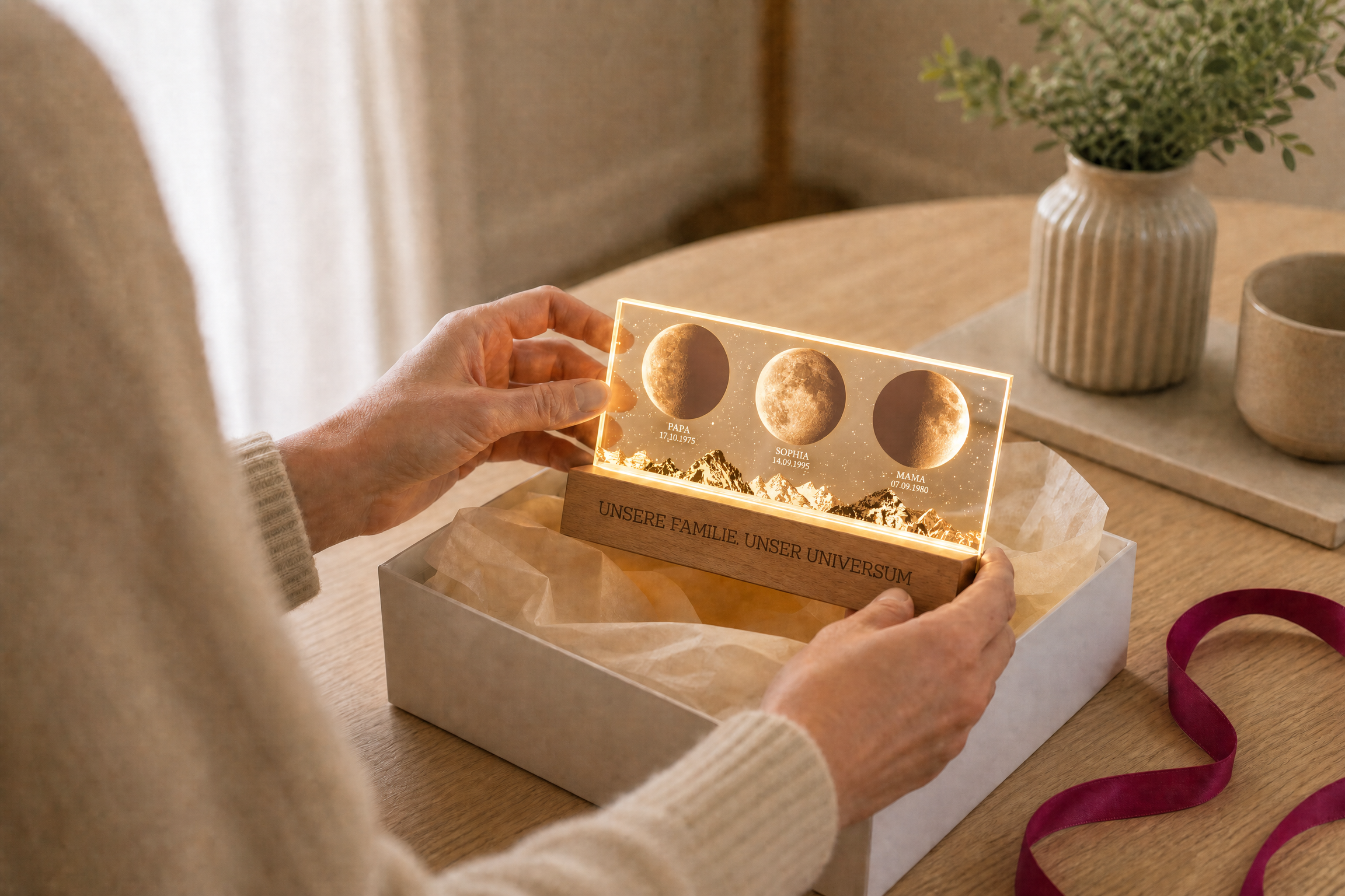 Hände heben ein personalisiertes Familien-Mondphasen-Nachtlicht aus einer Geschenkbox